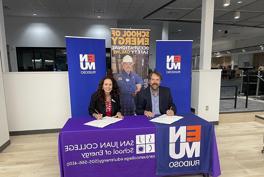 SJC President Dr. Pendergrass and ENMU President Trosper at table with ENMU, SJC, and School of Energy banners signing papers